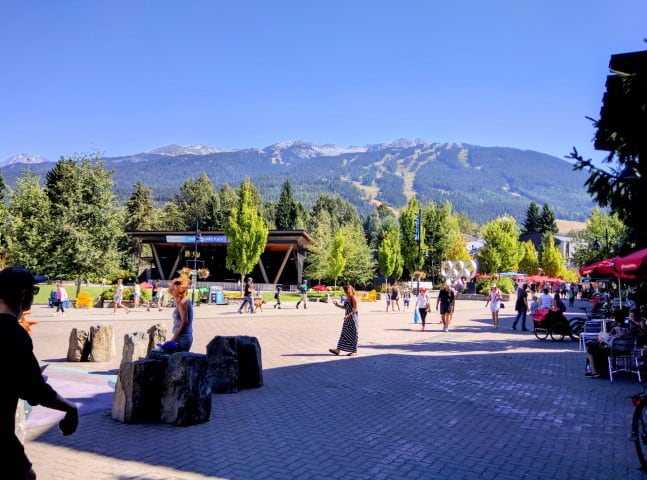 view of Olympic Village Whistler, B.C.. walking paths, shops, trees, and mountains in the background