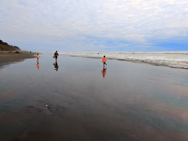 Man and two kids running on the beach in Olympic National Park